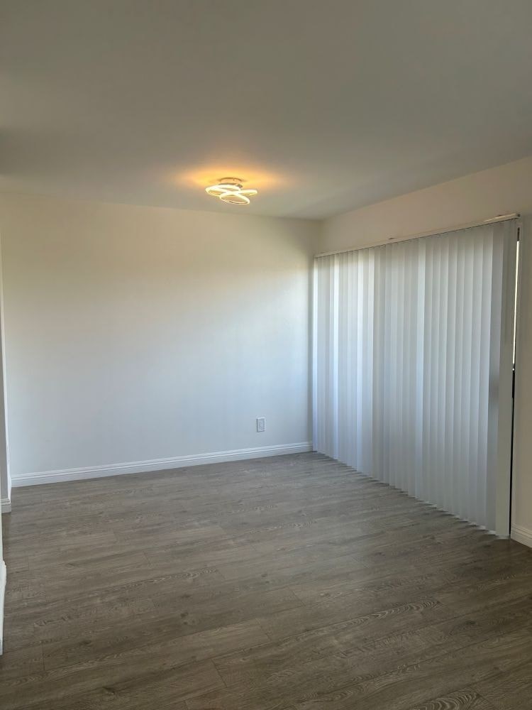 A room with a light on the ceiling and a window with blinds.