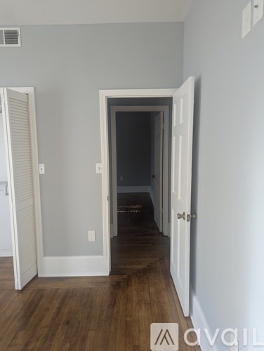 A room with a white door and a wooden floor.