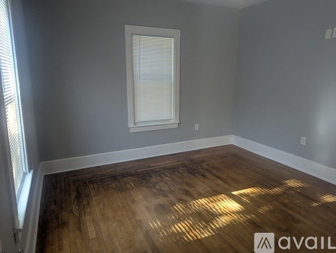 A room with wooden flooring and a window with blinds.