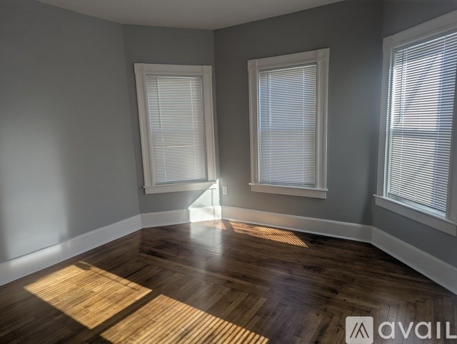 A room with wooden floors and two windows with blinds.