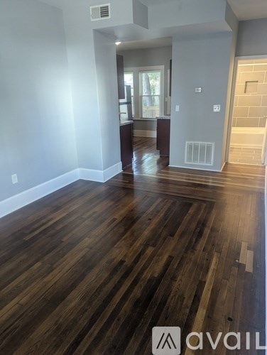 A room with wooden flooring and a wall-mounted air conditioner unit.