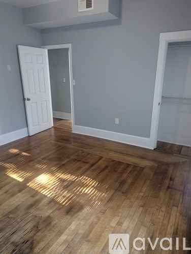 A room with wooden flooring and two white doors.