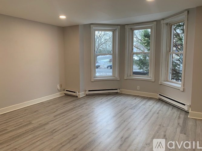 A room with wooden flooring and three windows.