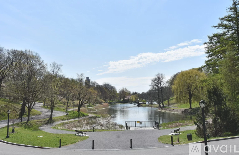 A park with a lake, trees, and benches.