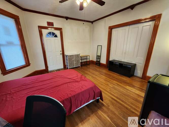 A bedroom with a red bedspread and a ceiling fan.