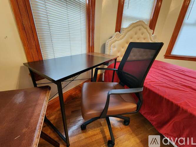 A brown leather chair sits in front of a black table with a laptop on it.