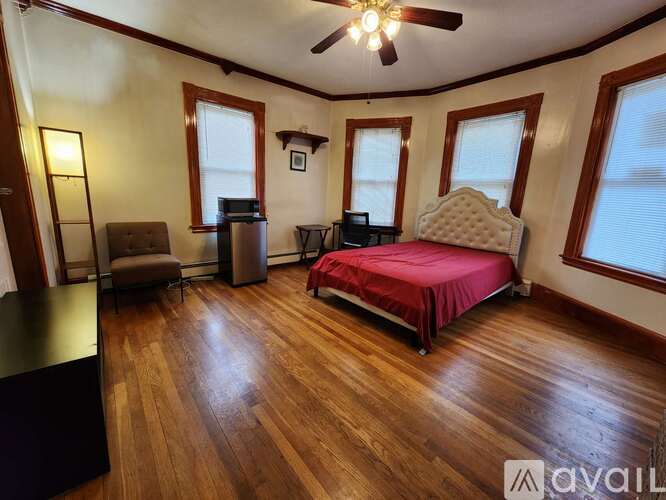 A bedroom with a bed, chair, and a ceiling fan.