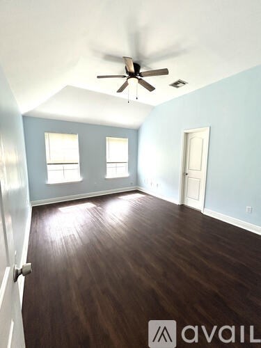 A room with a ceiling fan and wooden flooring.