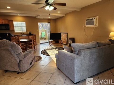 A living room with a grey couch and a fan.