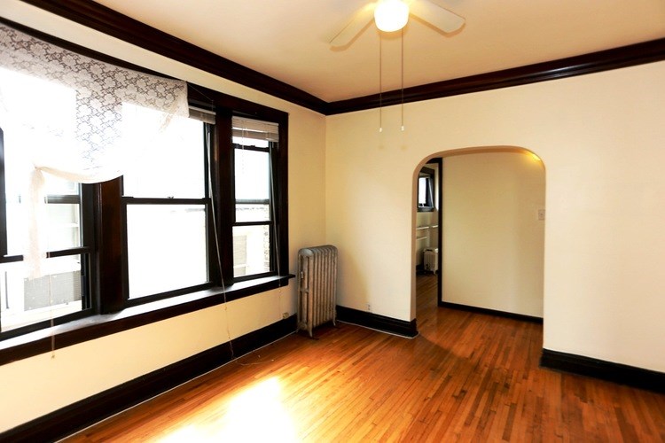 A room with a window and a fan on the ceiling.