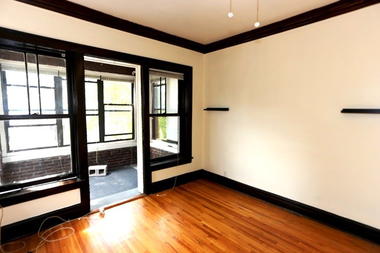 A room with wooden floors and a window overlooking a balcony.