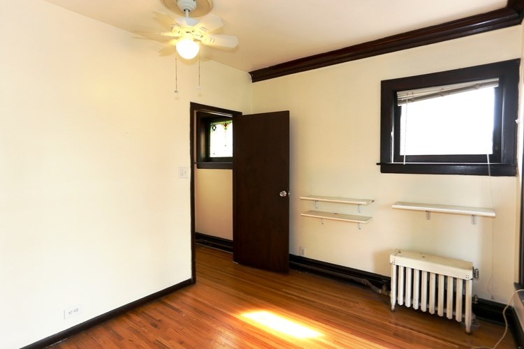 A room with a brown door and a window with white blinds.