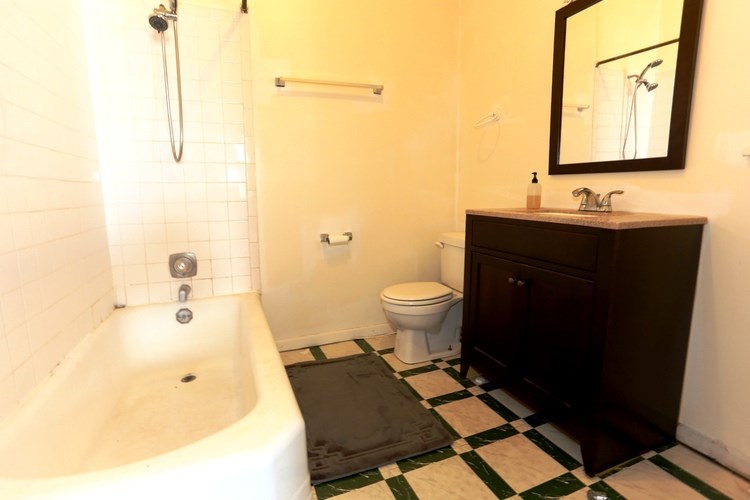 A white bathtub sits next to a toilet in a bathroom.
