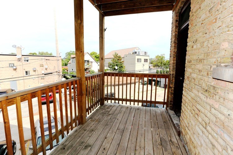 A wooden balcony with a brick wall on one side.