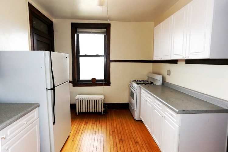 A kitchen with white cabinets and a white refrigerator.
