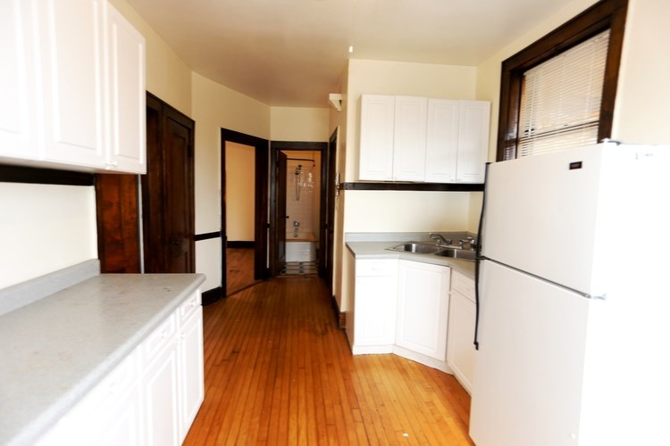 A kitchen with white cabinets and a wooden floor.