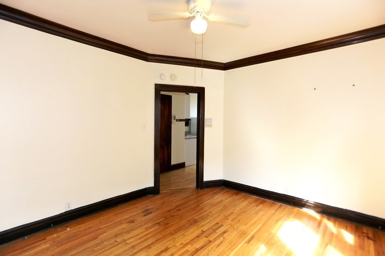 A room with a wooden floor and a ceiling fan.