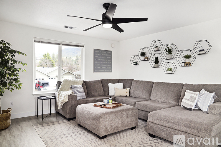 A living room with a grey couch, a small table, and a plant.