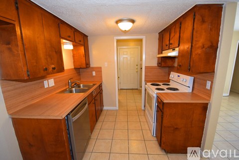 A kitchen with wooden cabinets and a stainless steel dishwasher.