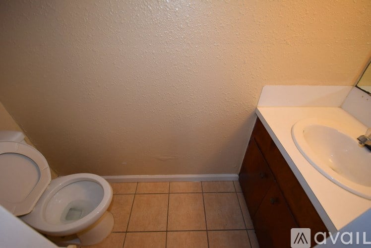 A bathroom with a toilet, sink, and tiled floor.