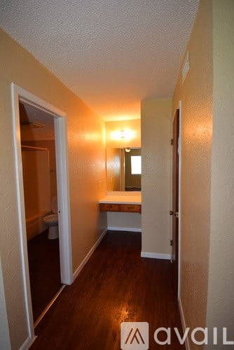 A hallway with a mirror and lights on the wall.