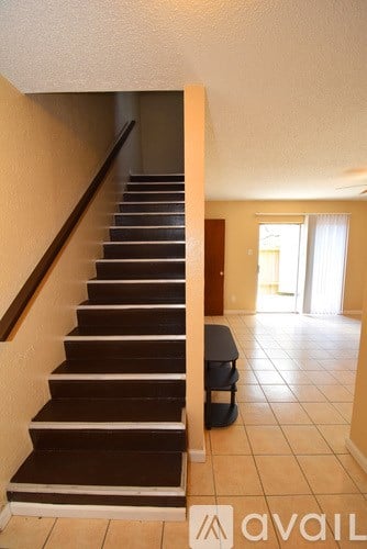 A staircase with a black handrail and wooden steps leading to a living room.
