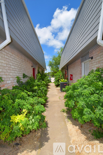 A narrow pathway between two buildings with a sign that reads "AVAIL" in the foreground.