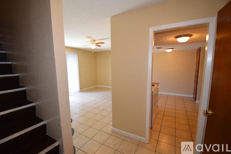 A hallway with a staircase on the left and a door on the right.