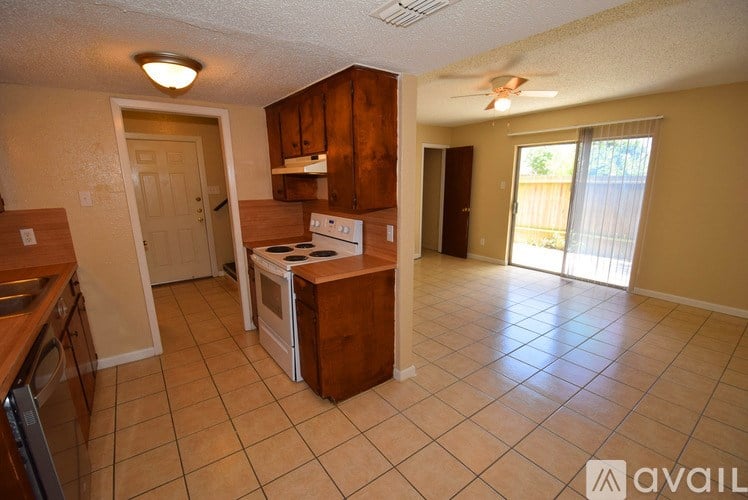 A kitchen with a white stove top oven and a fan on the ceiling.
