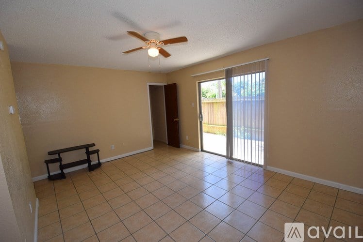 A room with a ceiling fan and sliding glass doors.
