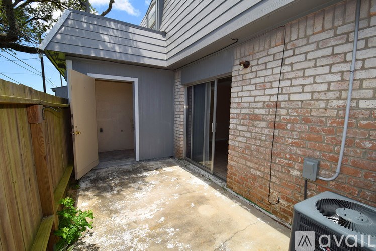 A backyard with a concrete patio and a brick wall.