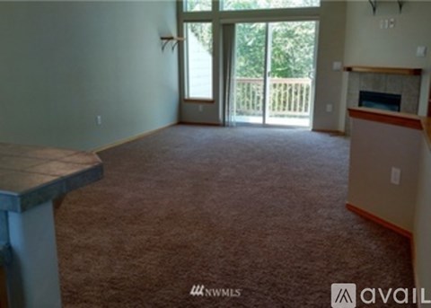 A living room with a carpet floor and a fireplace.