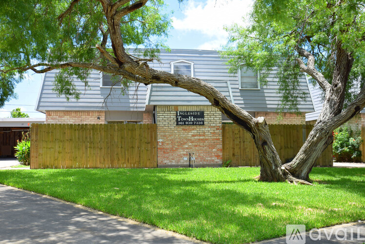 A tree in front of a house with a sign that says "In Laurel".