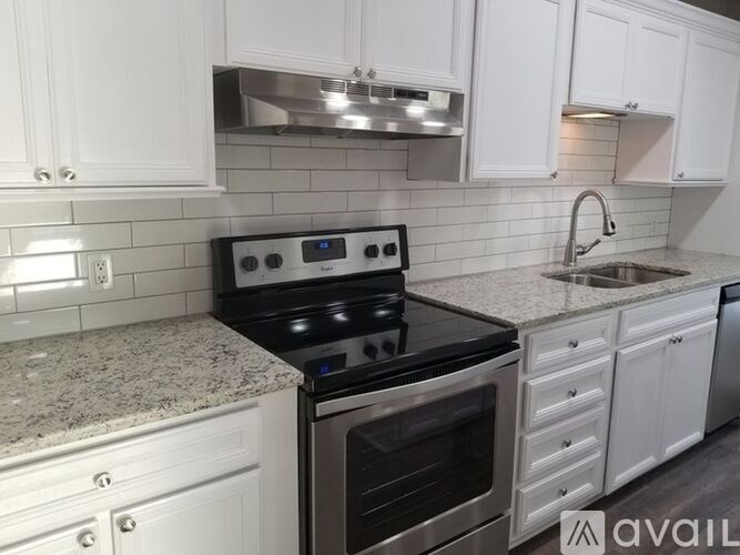 A kitchen with a black stove top oven and white cabinets.