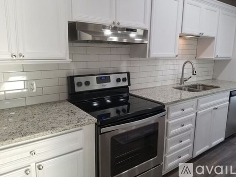 A kitchen with a black stove top oven and white cabinets.