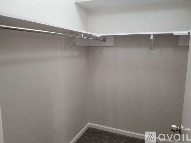 A small, empty room with a white wall and a grey carpet.