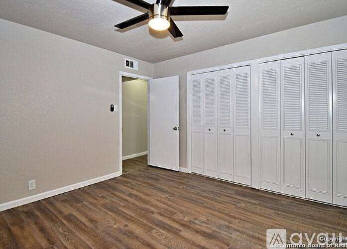 A room with a ceiling fan and wooden flooring.