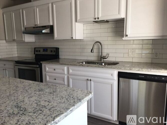 A kitchen with white cabinets and a granite countertop.