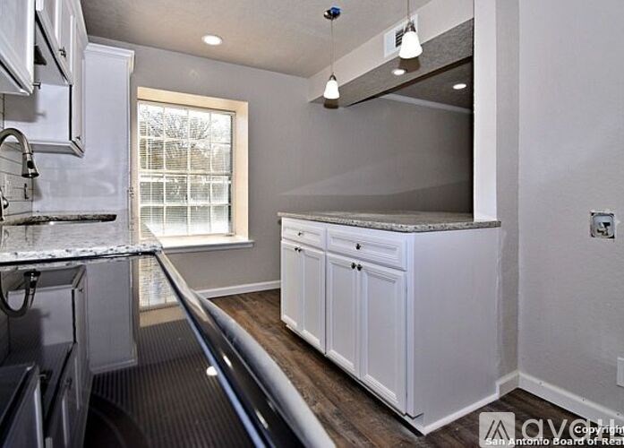 A kitchen with white cabinets and a window.