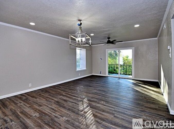 A room with wood flooring and a ceiling fan.