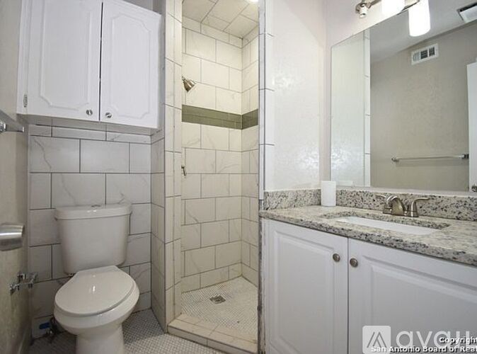 A white toilet is in a tiled bathroom with a walk-in shower.