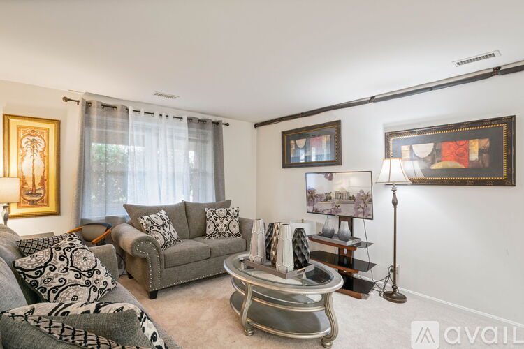 A living room with a grey couch, a coffee table, and a painting on the wall.