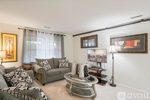 A living room with a grey couch, a coffee table, and a painting on the wall.