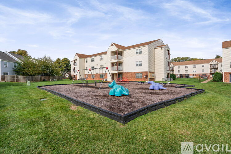 A playground area with a slide and a ball pit in the foreground, surrounded by apartment buildings.