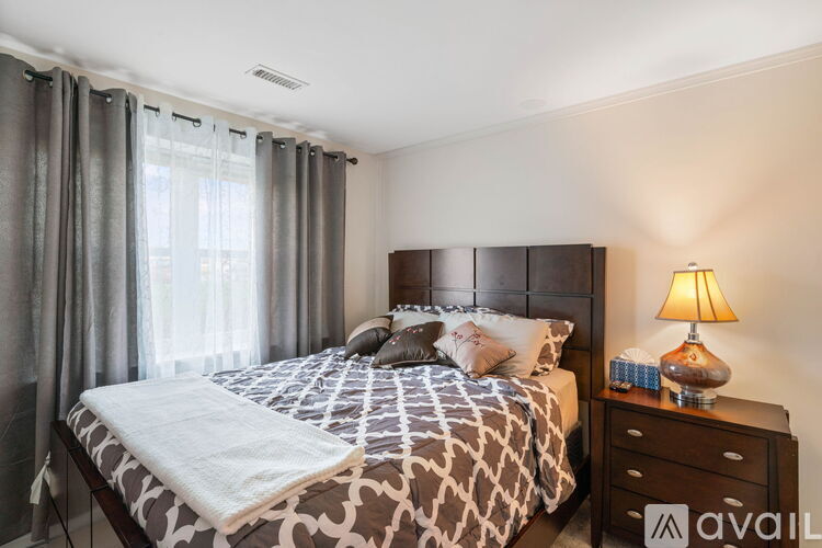A bedroom with a large bed and a lamp on the nightstand.
