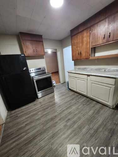 A kitchen with a black fridge, stove, and white cabinets.