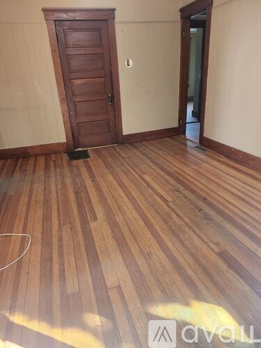 A room with wooden flooring and a door.