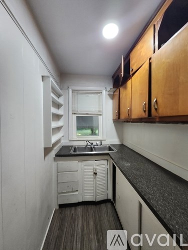 A kitchen with wooden cabinets and a window above the sink.