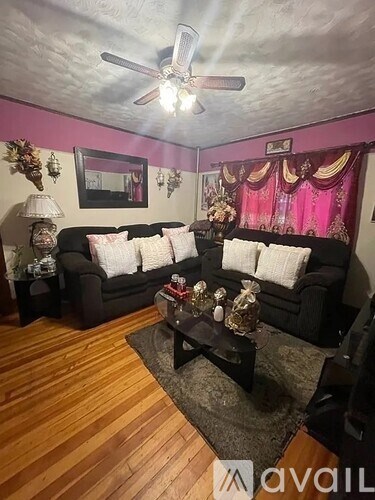 A living room with a black couch and a wooden floor.
