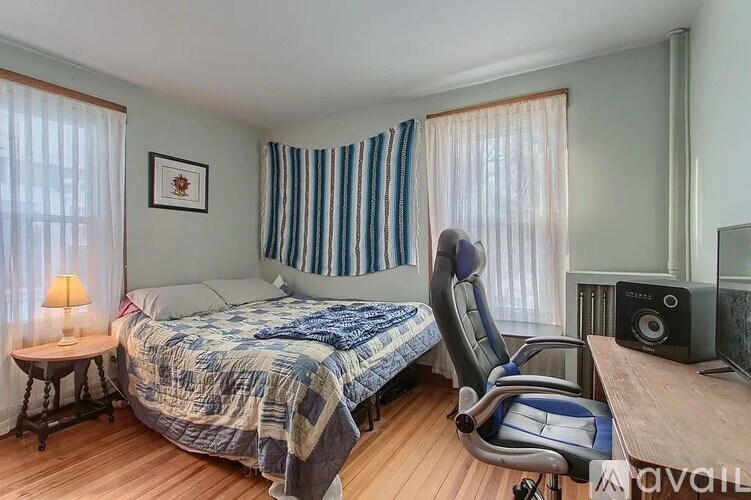 A bedroom with a bed, chair, and a lamp.